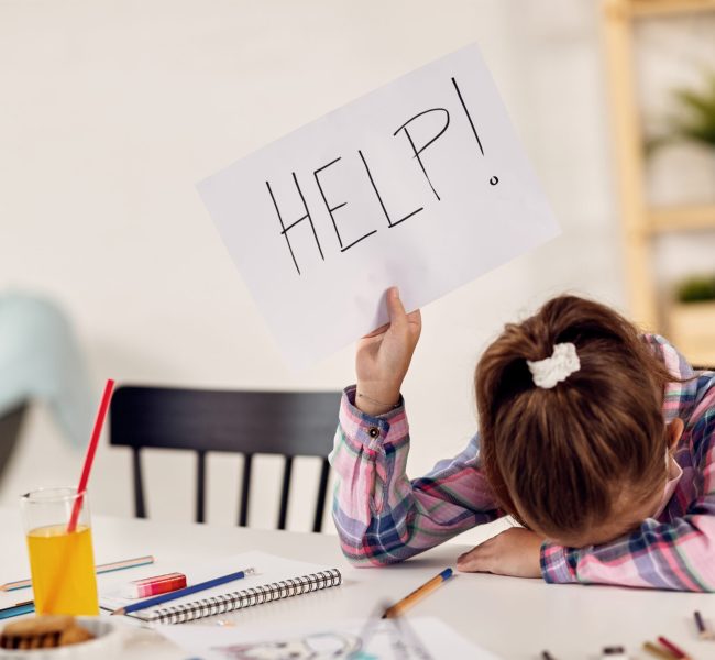 Small girl feeling desperate and holding HELP sing while homeschooling during virus epidemic.